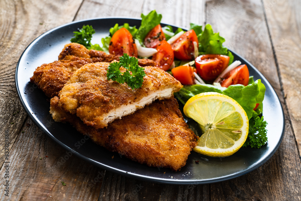 Pork chops with lemon and vegetable salad on wooden background Pork chops with lemon and vegetable salad on wooden background