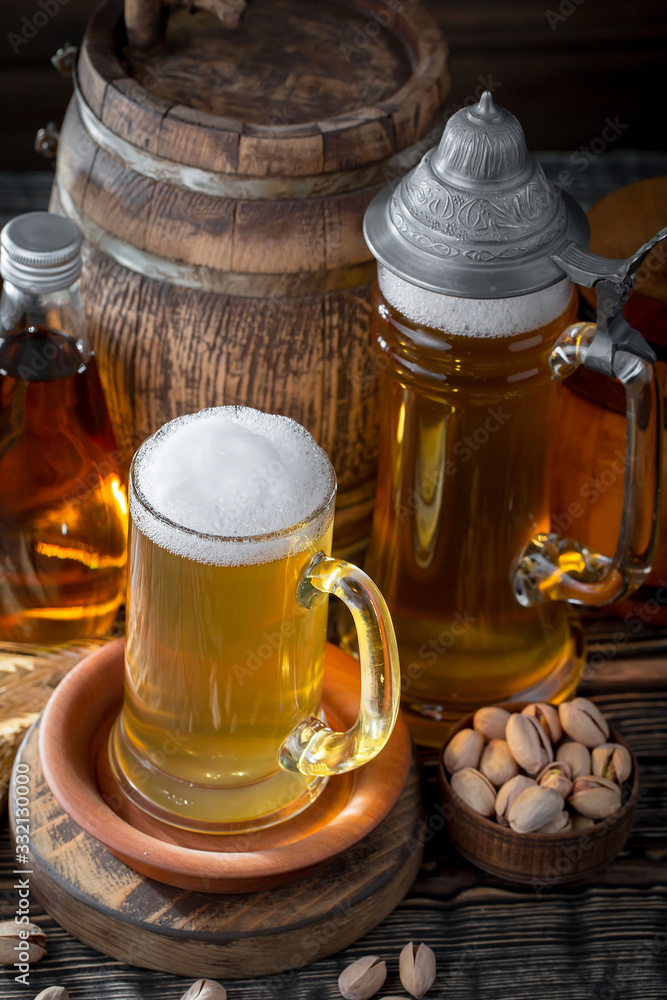 Light frothing beer in a glass, on an old background. Light frothing beer in a glass, on an old background.