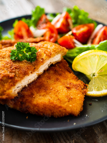 Pork chops with lemon and vegetable salad on wooden background