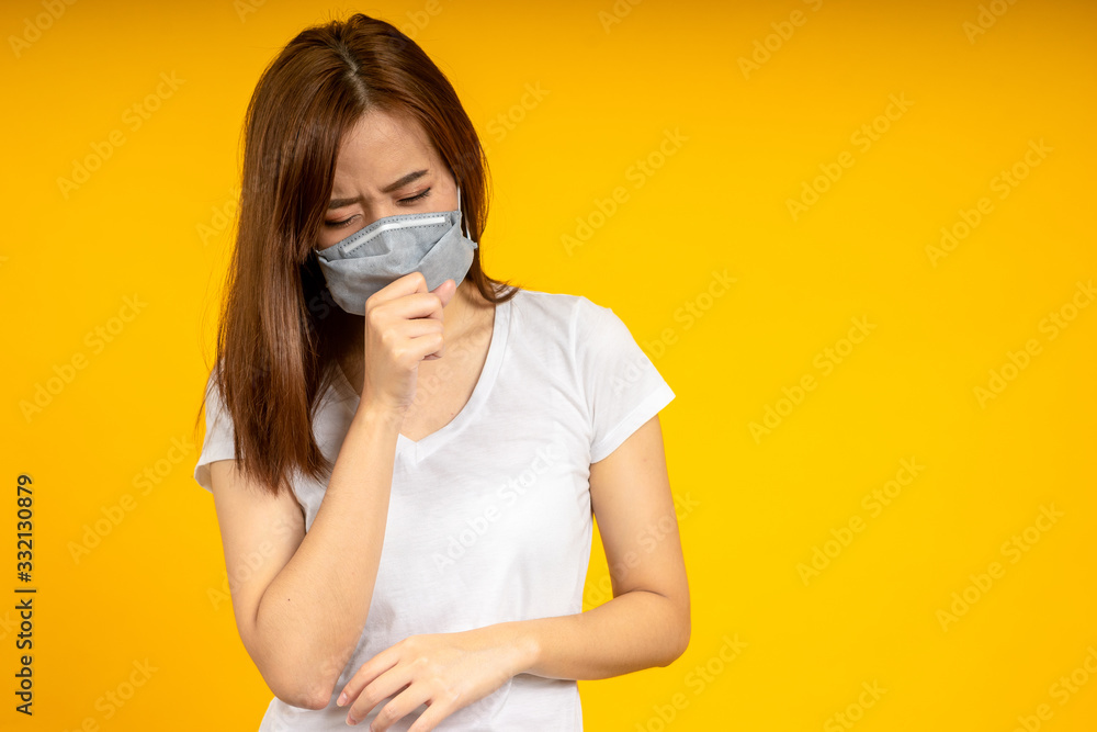 Asian woman is coughing or sneezing wearing hygienic mask to protect virus, COVID 19 or Colona Virus infection and dust PM 2.5 pollution isolate on yellow background Asian woman is coughing or sneezing wearing hygienic mask to protect virus, COVID 19 or Colona Virus infection and dust PM 2.5 pollution isolate on yellow background