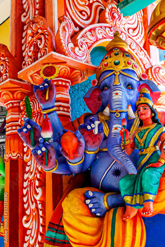 Representation of Hindu gods and tourists climbing a colorful stairs leading to the Batu Caves in the background. Kuala Lumpur, Malaysia photo