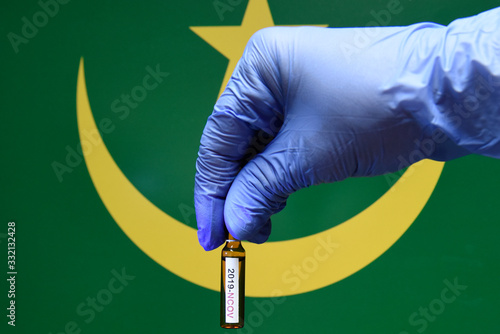 Corona virus or Covid-19 in Mauritania , sample blood tube in hand with Mauritania flag on background