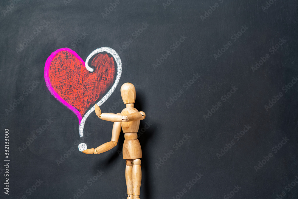 A wooden man stands next to a heart and a question mark drawn on a chalk board.