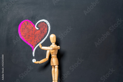 A wooden man stands next to a heart and a question mark drawn on a chalk board.