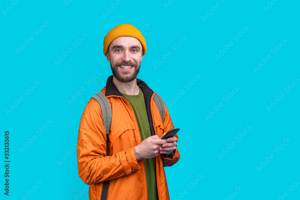 Half length studio portrait of casually dressed smiling male tourist with a backpack isolated over blue background Half length studio portrait of casually dressed smiling male tourist with a backpack isolated over blue background
