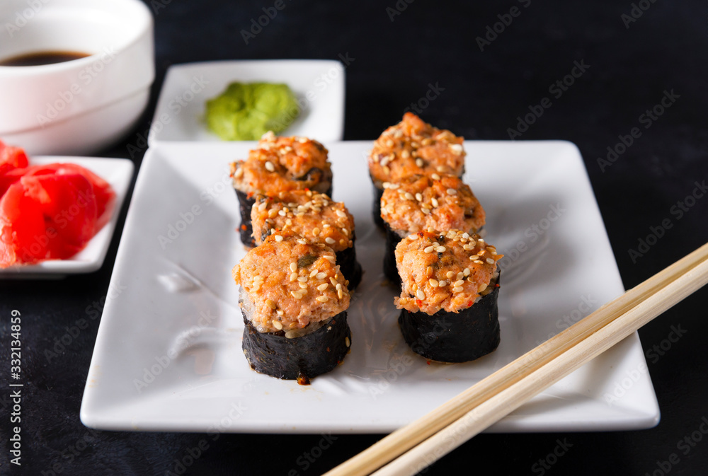 sushi , Japanese hot baked rolls with fish and sesame , ginger and wasabi, sticks on a white plate on a black background, sushi , Japanese hot baked rolls with fish and sesame , ginger and wasabi, sticks on a white plate on a black background,
