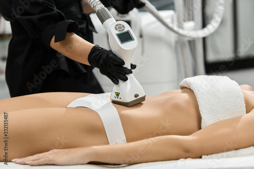 close-up of masseur arm using lpg massager on woman belly in beauty clinic