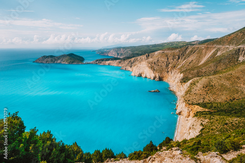 Kefalonia west coastline. Assos village town and Frourio peninsular. Beautiful blue bay with brown limestone rocks and white clouds on horizon. Greece