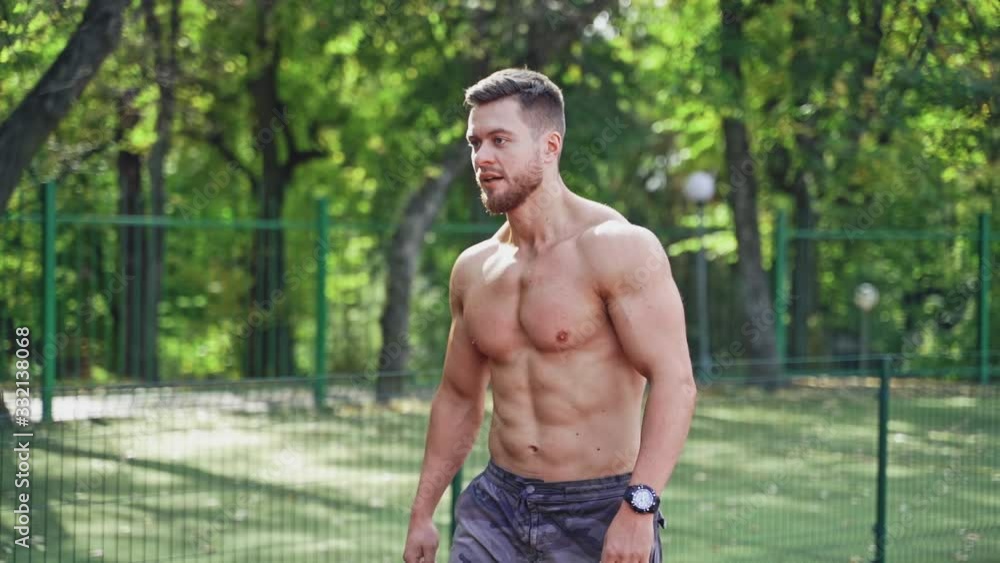 Muscular runner on the outdoor stadium. Portrait of a strong athlete without shirt prepares for running on a track. Slow motion. Muscular runner on the outdoor stadium. Portrait of a strong athlete without shirt prepares for running on a track. Slow motion.