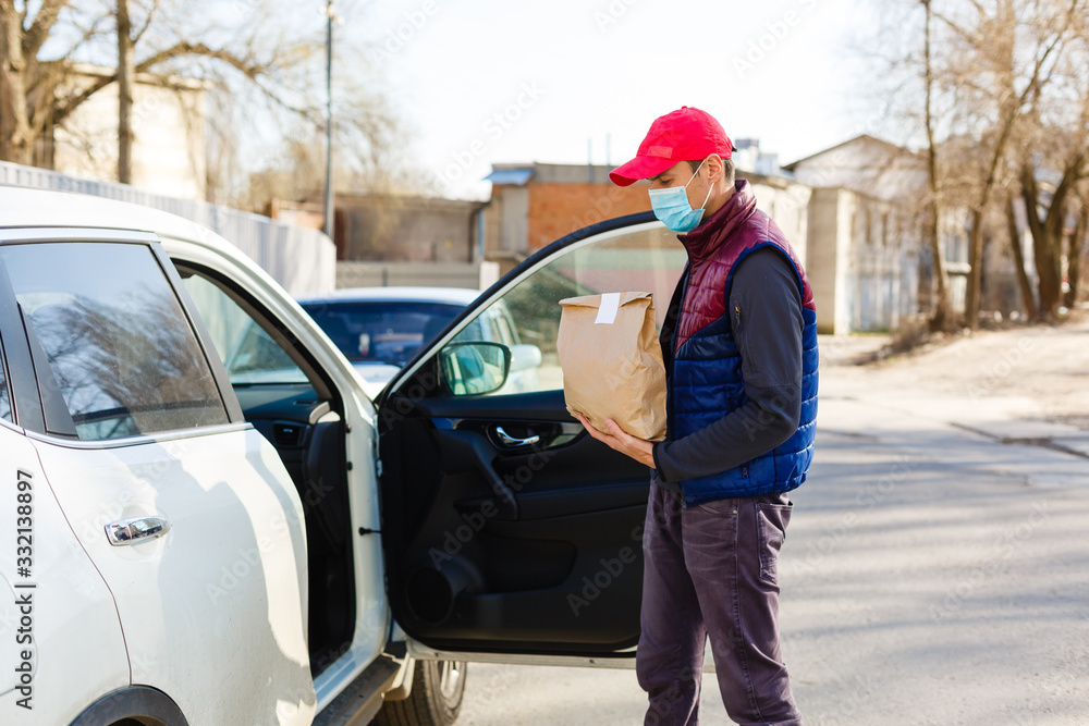 delivery by car. man in protective mask and medical gloves holding a paper box. Delivery service under quarantine, disease outbreak, coronavirus covid-19 pandemic conditions. delivery by car. man in protective mask and medical gloves holding a paper box. Delivery service under quarantine, disease outbreak, coronavirus covid-19 pandemic conditions.