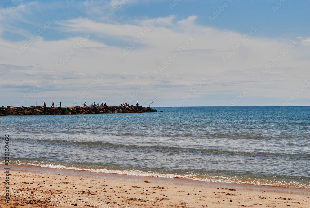 People fishing in the groynes on a bright day