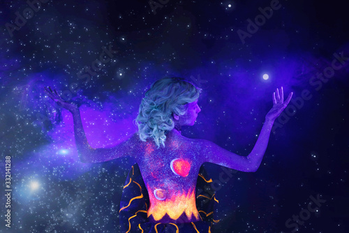 girl in ultraviolet light with body art on a black background in ultraviolet with smoke