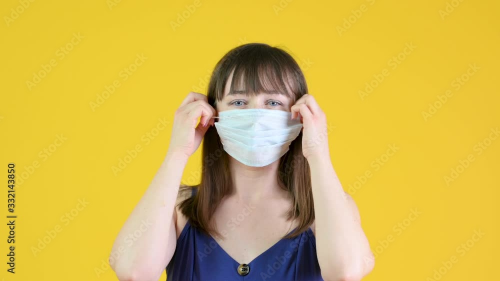 Young happy girl takes off a medical mask. Isolated on a yellow background. ealth care and medical concept.