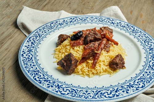 Light, diet pilaf with beef and carrots on a white plate on a wooden background. Top view with copy space for text. Traditional oriental cuisine