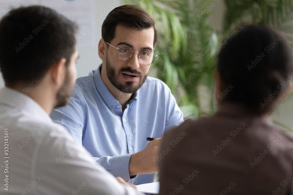 Diverse businesspeople sit at desk in office talk brainstorm discuss business ideas together, concentrated colleagues gather at meeting in boardroom consider project at briefing, cooperation concept Diverse businesspeople sit at desk in office talk brainstorm discuss business ideas together, concentrated colleagues gather at meeting in boardroom consider project at briefing, cooperation concept