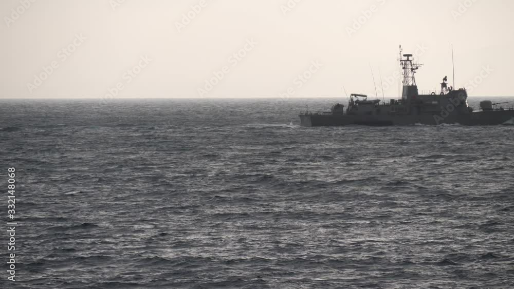 Military battleship sailing across ocean waves on windy coastal seascape Military battleship sailing across ocean waves on windy coastal seascape