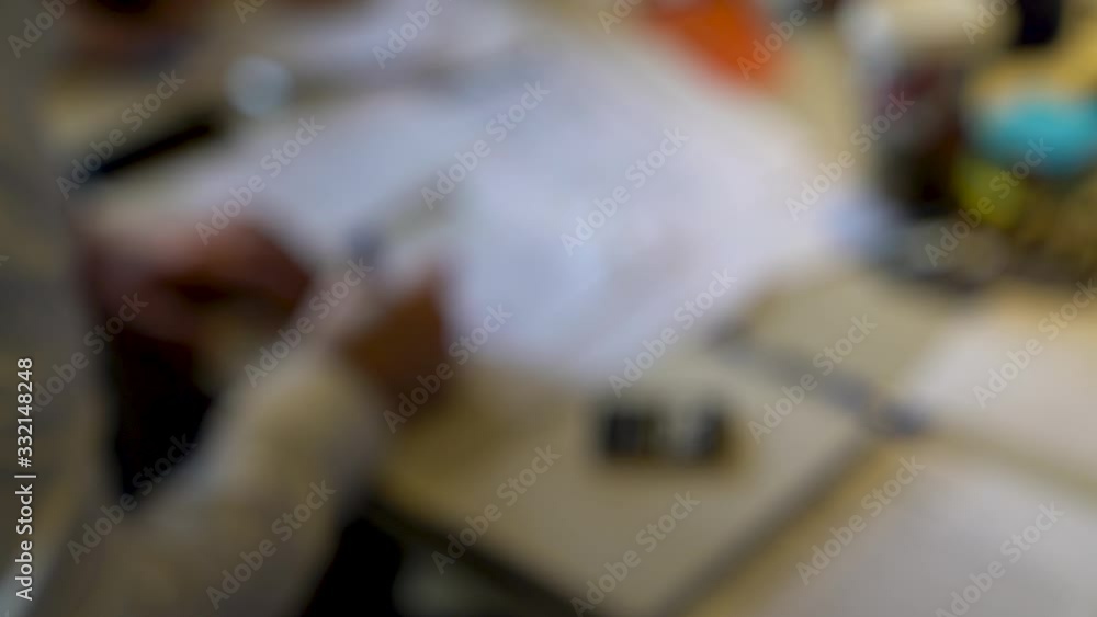 Unidentified business person writing ideas on notebook, brainstorming ideas. Video is shot out of focus intentionally and originally Unidentified business person writing ideas on notebook, brainstorming ideas. Video is shot out of focus intentionally and originally