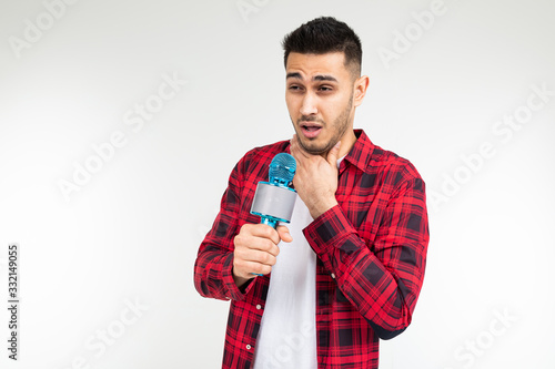 male presenter with a microphone in his hands has a sore throat on a white isolated studio background