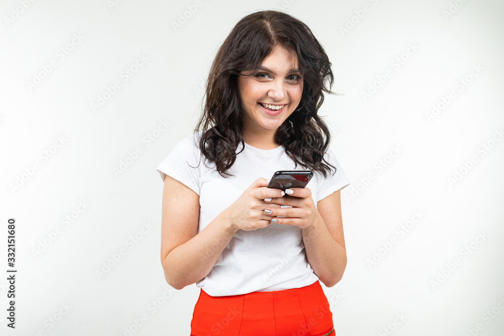 girl smiles and writes a message by phone on a white studio background girl smiles and writes a message by phone on a white studio background