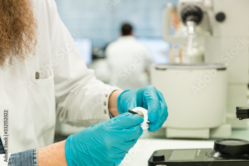 Closeup of man s hand in gloves preparing machine to perform analysis of sample suspected for coronavirus infection. Covid-19 pandemics laboratory diagnosis.