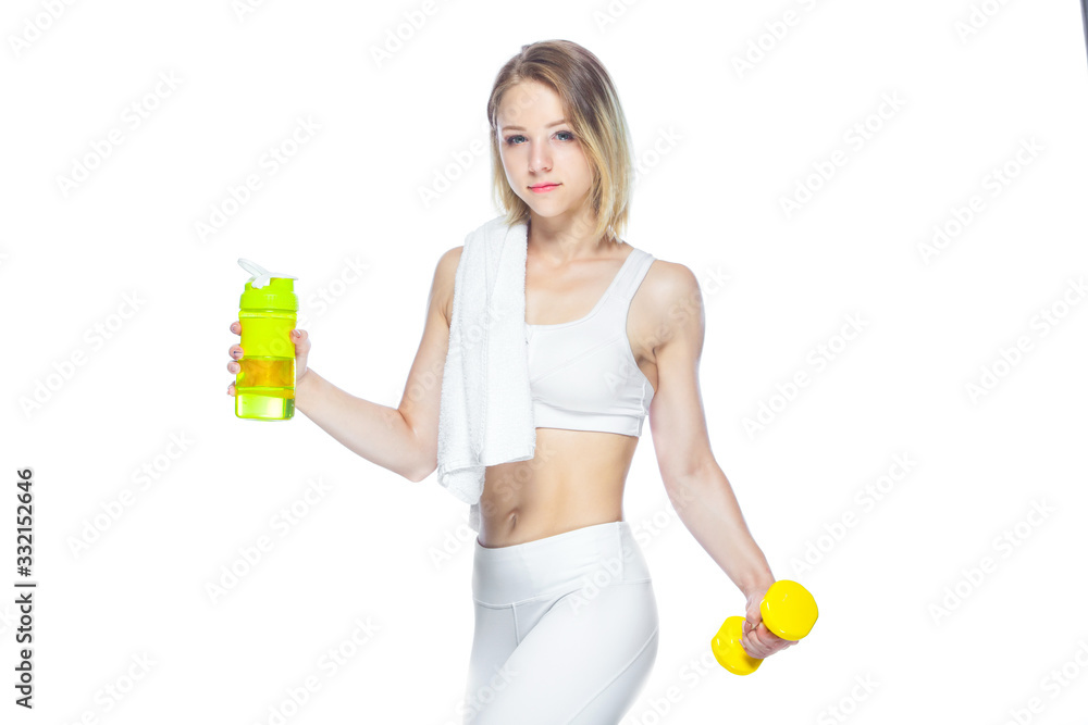 Beautiful young sportswoman holding a bottle of water, a towel and a dumbbell over white background Beautiful young sportswoman holding a bottle of water, a towel and a dumbbell over white background