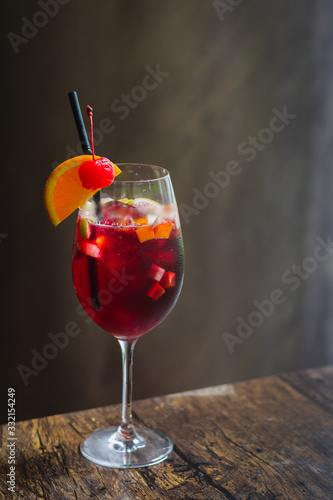 a glass of sangria in a tall glass with a wedge of orange and cherry