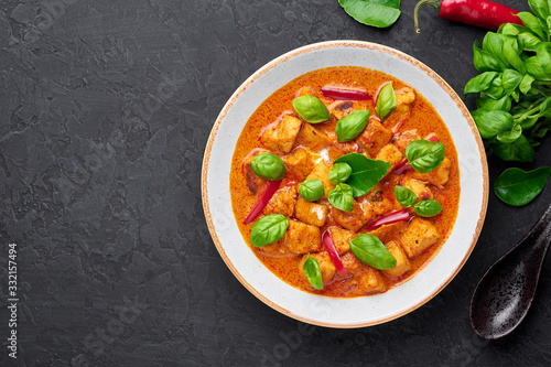 Thai Panang Chicken Curry in white plate at black slate background. Phanaeng Curry is thai cuisine dish with chicken  kaffir lime leaves  red curry sauce and vegetables. Thai food. Copy space