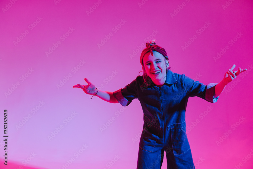 Obraz premium Young stylish girl dancing in the Studio on a colored neon background. Music dj poster design.