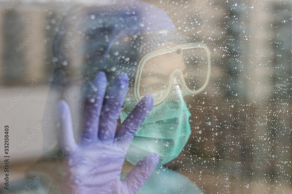 Fototapeta premium Photo of nurse inside hospital, with protective equipment for coronavirus, isolated due to quarantine. Rainy day.