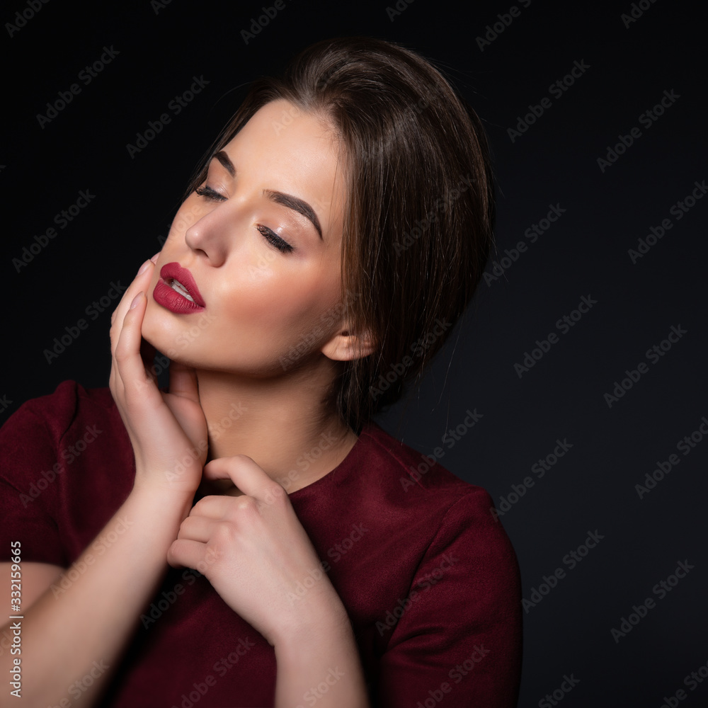 Portrait of attractive young woman over black background. Amazing girl with perfect makeup wearing elegant deep red dress. Beauty and fashion Portrait of attractive young woman over black background. Amazing girl with perfect makeup wearing elegant deep red dress. Beauty and fashion