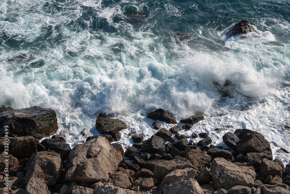 Fototapeta premium Sea waves breaking on the rocky shore, view from top