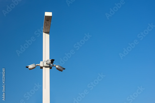 Three CCTV cameras on a lamppost with blue sky background and free space