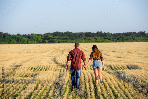 pair of falling in love идут on the field of wheat in summer for a hand from a back