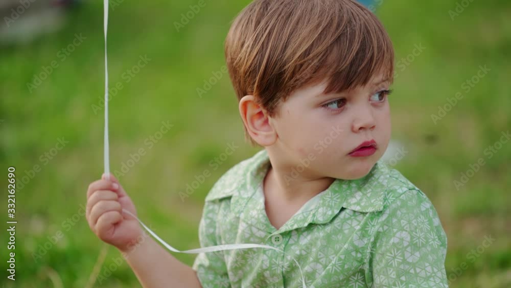 Portrait of baby boy on green nature background. Cute little boy sitting on the green grass and holding rope with a balloon. Portrait of baby boy on green nature background. Cute little boy sitting on the green grass and holding rope with a balloon.