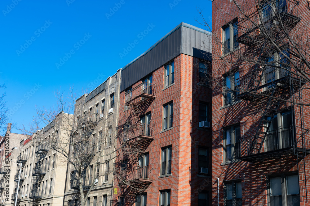 A Row of Old Brick Residential Buildings with Fire Escapes in Astoria Queens of New York City A Row of Old Brick Residential Buildings with Fire Escapes in Astoria Queens of New York City