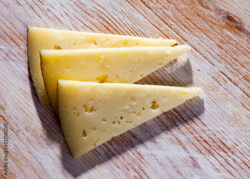 Slice of semi-hard cheese on a wooden table