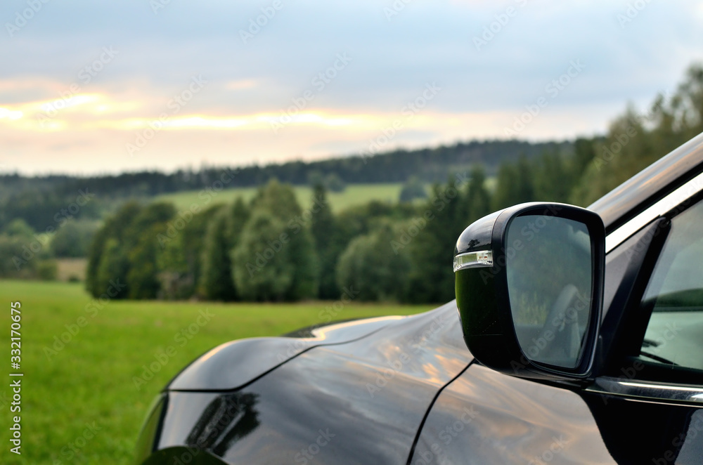Part of modern black SUV crossover car vehicle in nature. Front rear view mirror.