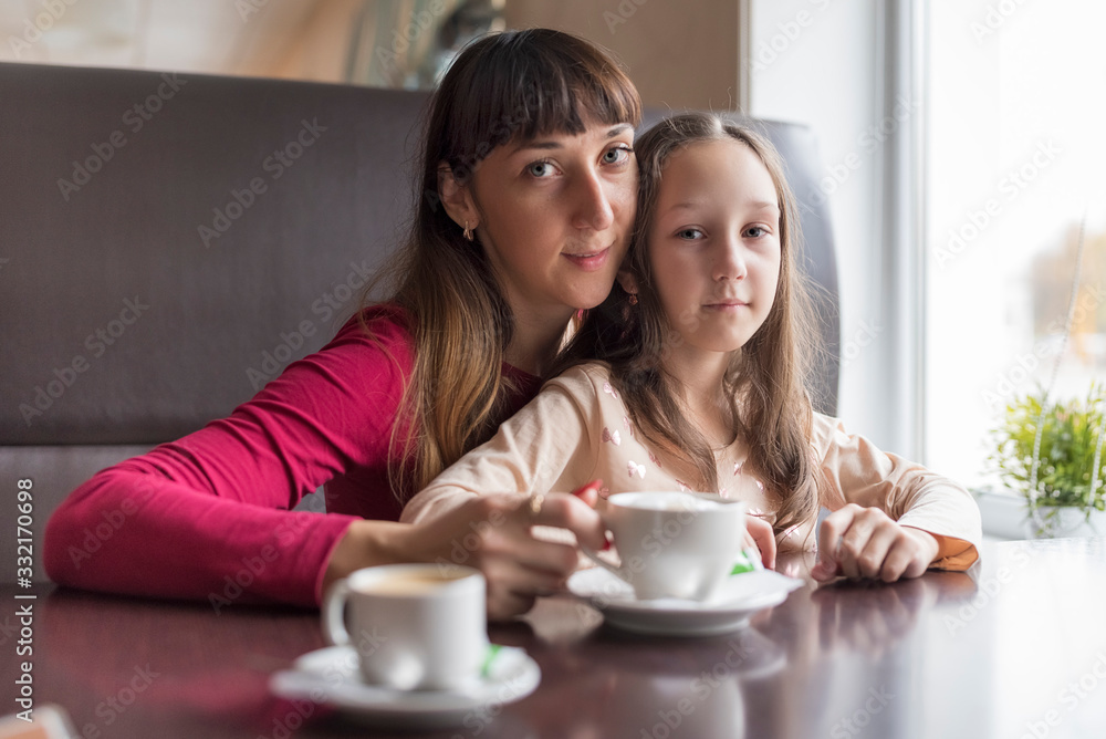 Mom and daughter are drinking coffee in a cafe. Photographed close-up. Mom and daughter are drinking coffee in a cafe. Photographed close-up.