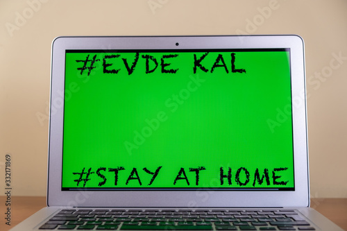 Writing attention message on notebook geenscreen reminder stay home (Turkish mean  "Evde Kal").  Covid-19.Stay at home in time of pandemic concept.