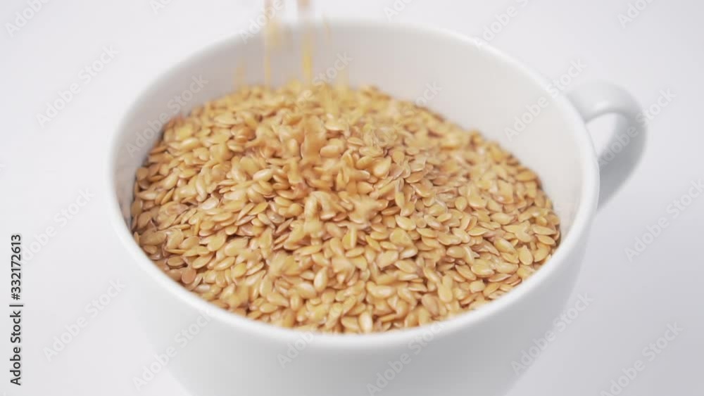 Flax seeds fill a tea white cup close-up. Slow fall. Flax seeds fill a tea white cup close-up. Slow fall.