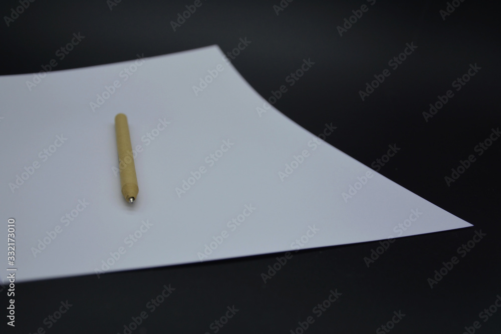 sheet of white paper on a black background and pen sheet of white paper on a black background and pen