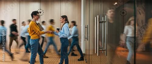 Business people handshaking on background of crowd office employees at coworking center. People at motion blur. Concept of working at action. Group of coworkers at open space. Wide image photo