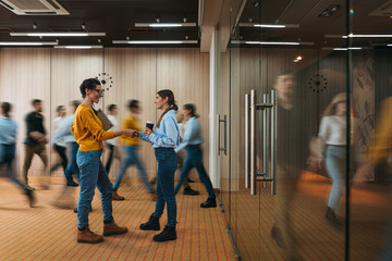 Businesswoman discussing on background of crowd office employees at coworking center. Business people at motion blur. Concept of working at action. Group of coworkers at open space