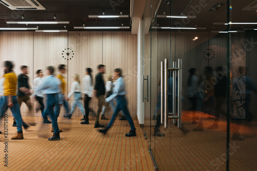 Group of office employees at coworking hall. Business people walking at modern open space. Motion blur. Concept