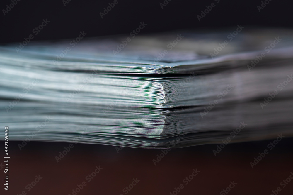 A stack of hundred dollar bills against a dark background. Photographed close-up. A stack of hundred dollar bills against a dark background. Photographed close-up.