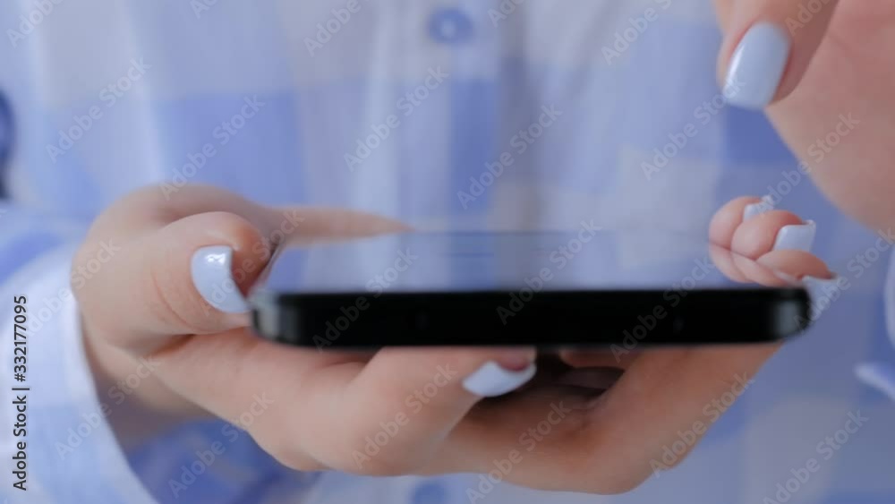 Relax, entertainment, leisure time and technology concept. Close up view - woman hands using black smartphone with touchscreen display in living room or office - scrolling and touching