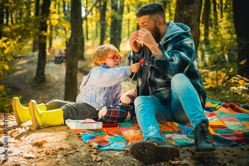 Education upbringing and development. Kid play doctor with dad nature background. Games on fresh air. Prevent illness. Doctor child stethoscope examine patient. Boy in doctor uniform treat patient