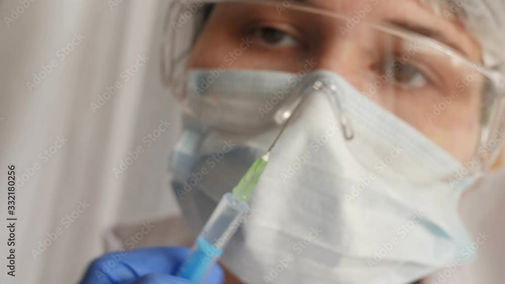 doctor looking at needle, vaccine, drops of syringe, preparing for injection