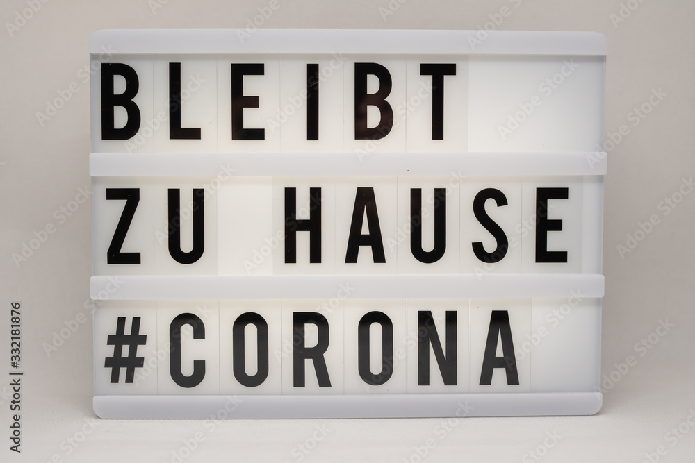 Obraz premium is written on an illuminated panel with black letters: Stay at home #Corona