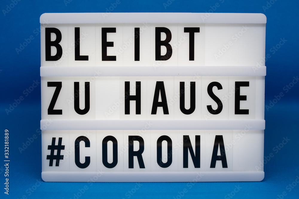 is written on an illuminated panel with black letters: Stay at home #Corona is written on an illuminated panel with black letters: Stay at home #Corona